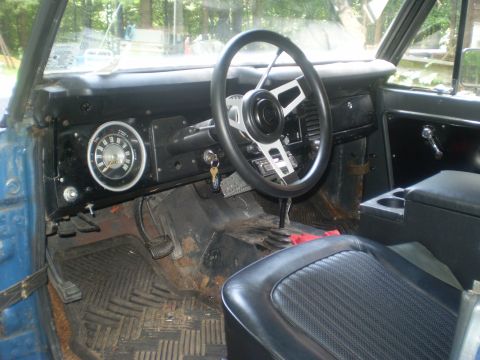 1979 Ford Bronco - The interior of a blue Ford Bronco, an aftermarket steering wheel and a visible gauge cluster.