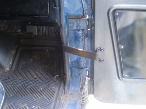 1979 Ford Bronco - Close-up view of the interior door frame and textured floor mat of a blue vehicle.