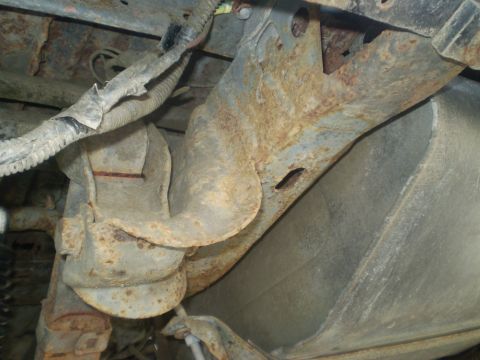 1979 Ford Bronco - Undercarriage view shows significant rust on metal components and a bundle of wiring.