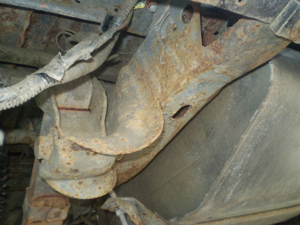 Rusted metal brackets and wiring harness under a vehicle