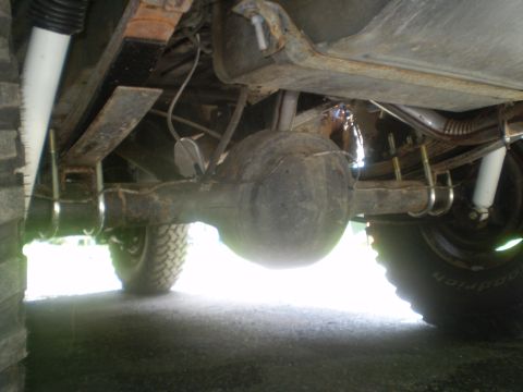 1979 Ford Bronco - This image shows the underside of a vehicle, focusing on the rear axle, leaf springs, and shocks, with a Supermotors.net watermark visible.
