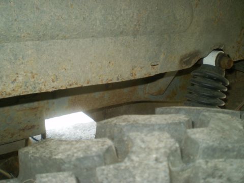 1979 Ford Bronco - Close-up view of a vehicle's rusted frame and tire, with a shock absorber visible.