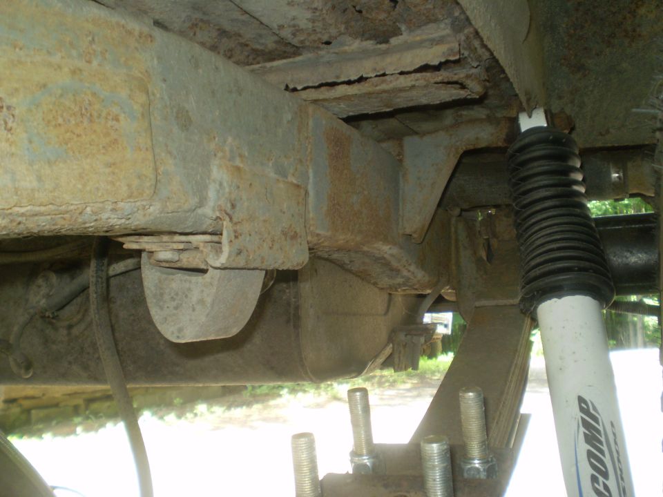 Undercarriage view showing rusty frame, leaf springs, and a shock absorber with 'AMP' logo. Supermotors.net watermark visible