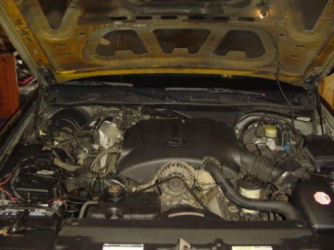 2000 Ford Crown Victoria - The engine compartment of a Ford Crown Victoria is visible with the hood open, revealing the motor and associated parts.