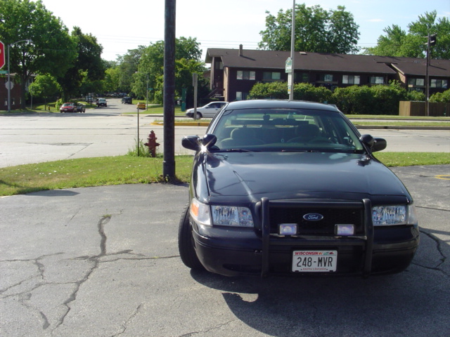 Black 2000 Ford Crown Victoria Police Interceptor with push bar, parked on cracked asphalt