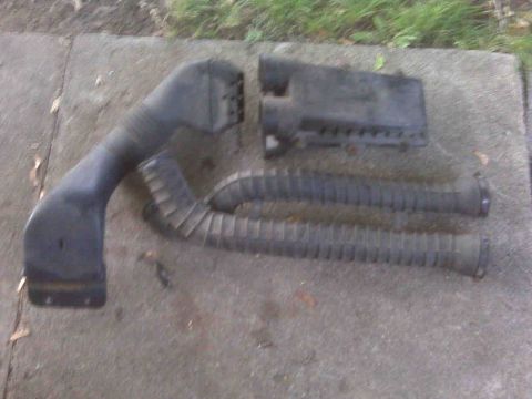 1995 Ford Bronco - Air intake components laid out on a concrete surface.