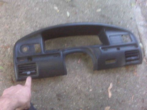 1995 Ford Bronco - A black dashboard trim piece, likely from an older vehicle, is shown with air vents and a finger pointing to one of the vents.