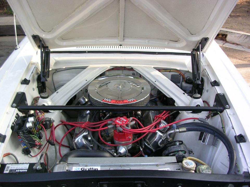 Engine bay of a white classic Ford Mustang with chrome air cleaner
