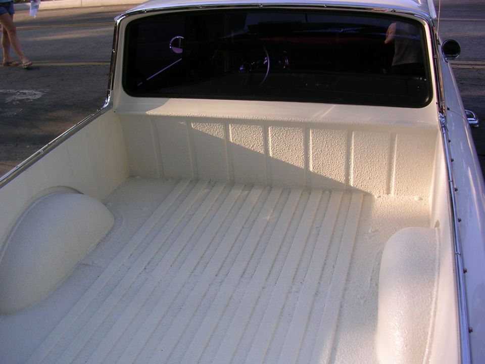 Empty white bedlined pickup truck cargo bed seen from the cab