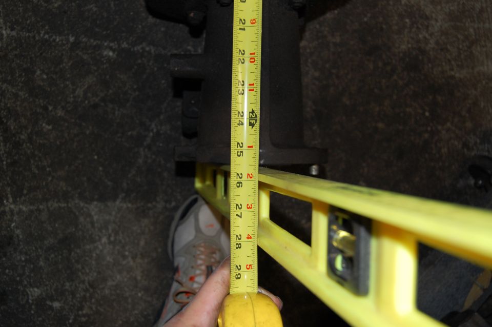 Measuring a black vehicle part with a tape measure and a yellow level
