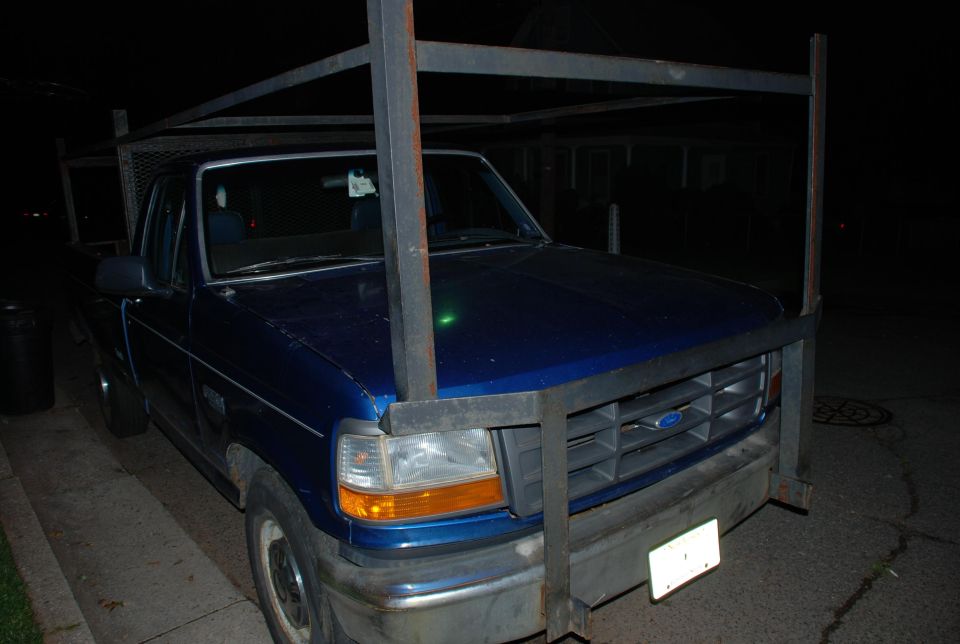 Blue Ford extended-cab pickup at night with welded steel ladder rack over cab and bed