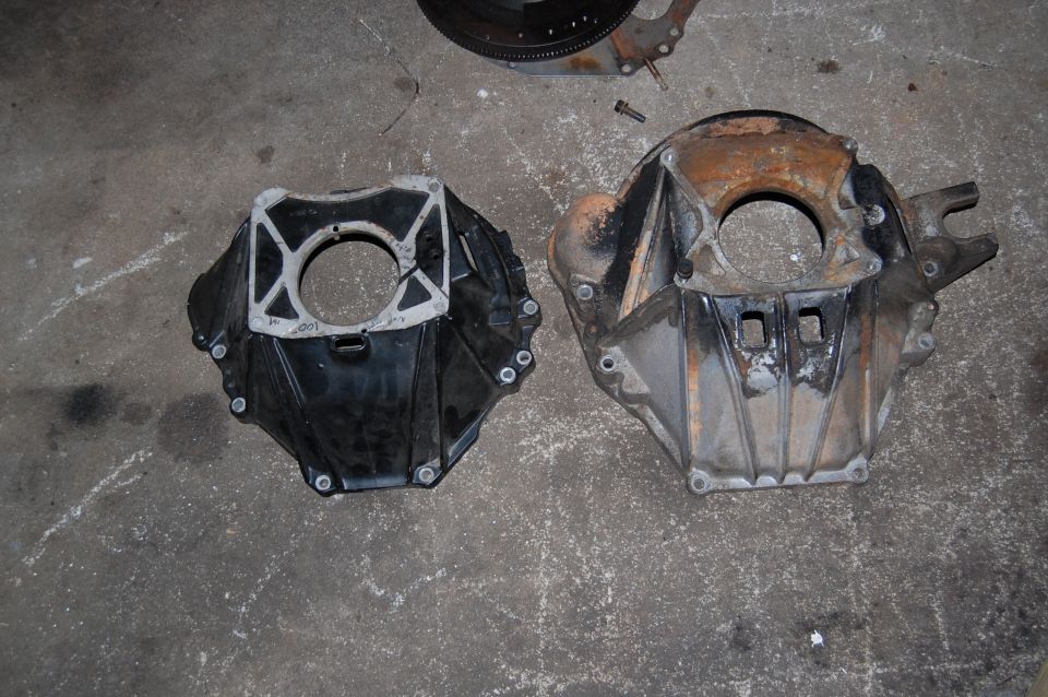 Two transmission bell housings, one black, one rusty aluminum