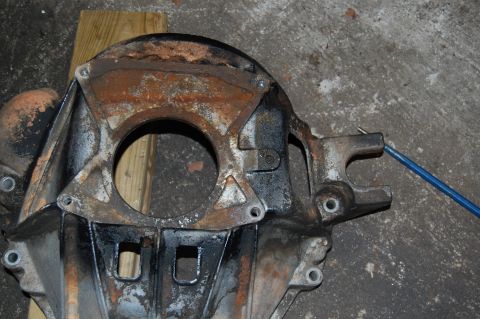 1994 Ford Bronco - A heavily rusted metal component, possibly an axle housing, with a blue cable attached.