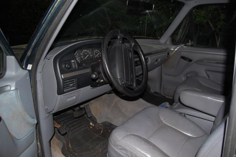 1994 Ford Bronco - The interior of a Ford Bronco, with gray seats and dashboard, is visible from the driver's side.
