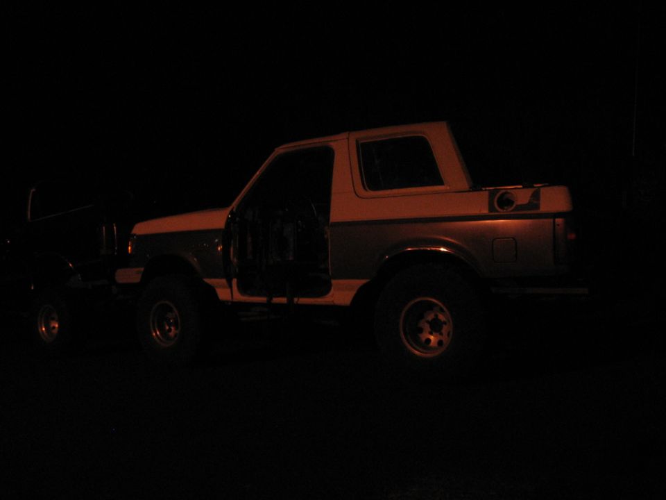 1989 Ford Bronco with doors open, parked next to another vehicle at night