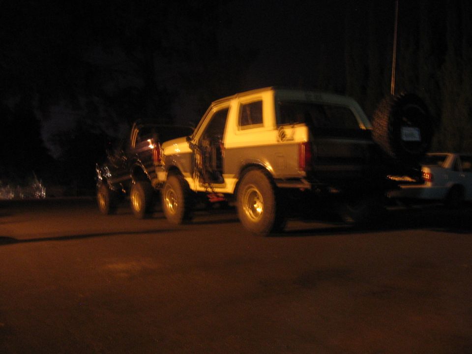 1989 Ford Bronco and another SUV parked at night, rear view