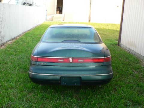 1990 Lincoln Mark VII - Rear view of a green 1990 Lincoln Mark VII parked outdoors on a grassy area.
