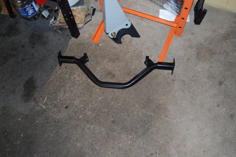 1994 Ford Bronco - A black metal bar with mounting brackets is shown on a concrete floor with other garage items.