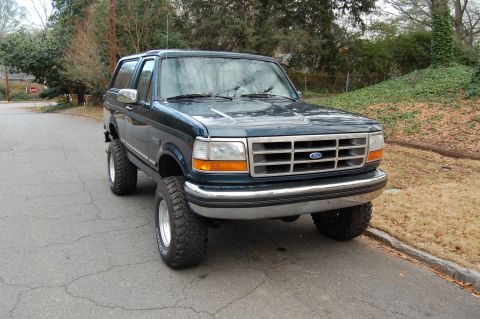 1994 Ford Bronco - This lifted 1994 Ford Bronco is shown from a front three-quarter angle on a paved road.