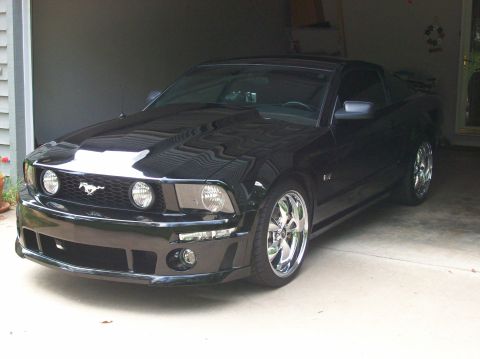 2007 Ford Mustang - A black 2007 Ford Mustang is parked in a garage, showing off its chrome wheels and design.