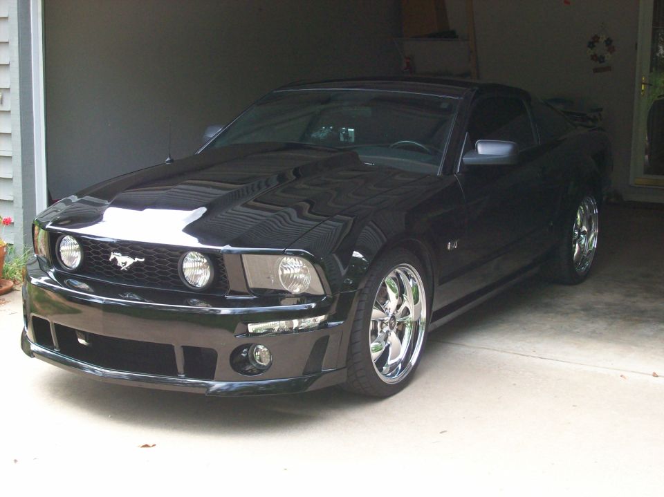 Black 2007 Ford Mustang parked in a garage with chrome wheels
