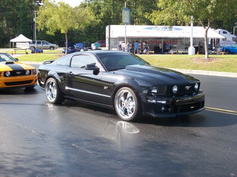 2007 Ford Mustang - A black Ford Mustang GT is parked next to a yellow and black Mustang.