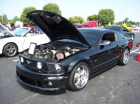 2007 Ford Mustang - Black 2007 Ford Mustang GT at a car show, hood open, with a white Mustang convertible nearby.