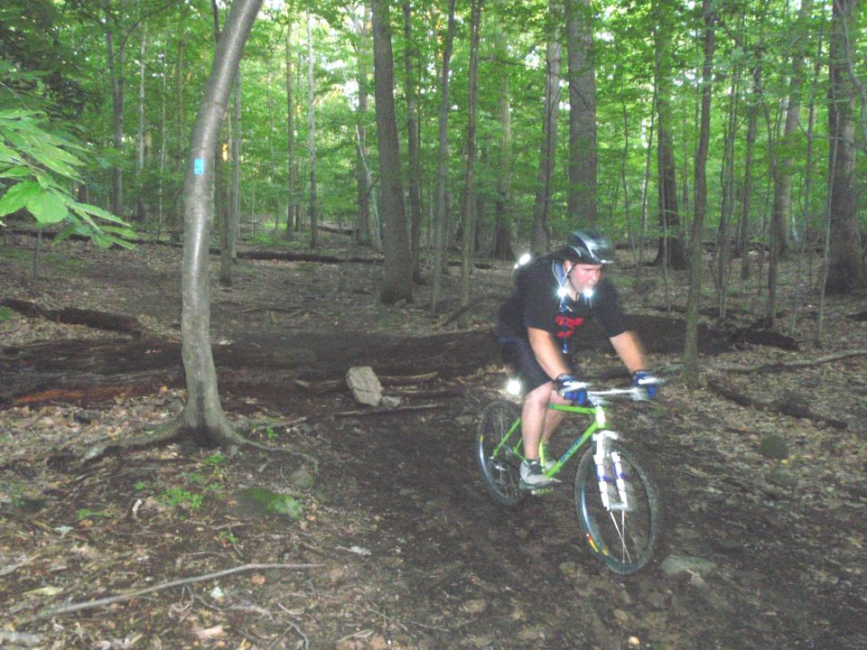 Green mountain bike with rider on a dirt trail in a forest