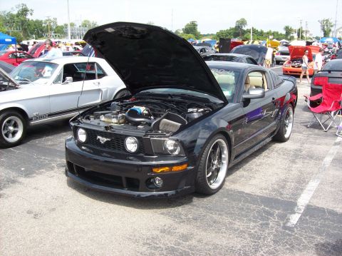 2007 Ford Mustang - A black 2007 Ford Mustang is displayed with its hood up at an outdoor car show.