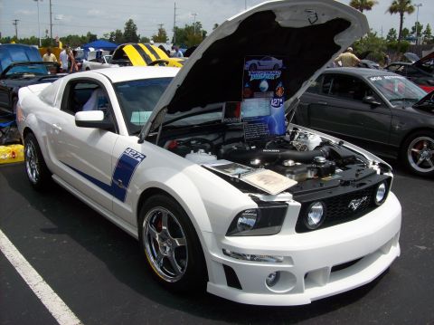 2007 Ford Mustang - White 2007 Ford Mustang on display with hood open, another Mustang visible in background.