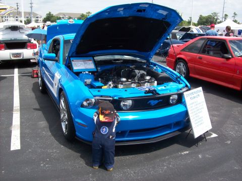 2007 Ford Mustang - A blue 2007 Ford Mustang is displayed with its hood open, a child inspects the engine bay.