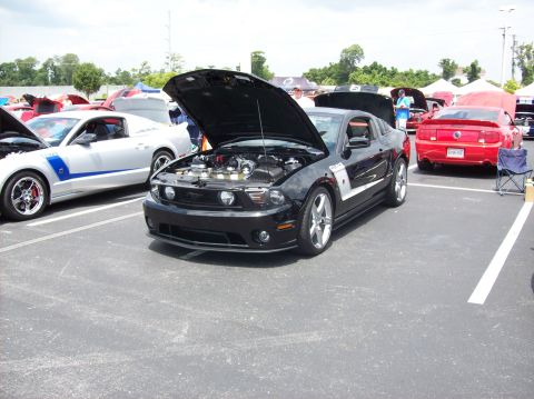 2007 Ford Mustang - Black 2007 Ford Mustang on display with its engine exposed, other Mustangs nearby.
