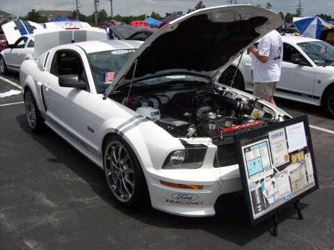 2007 Ford Mustang - A white Ford Mustang is displayed with its hood open, the engine and a presentation board.