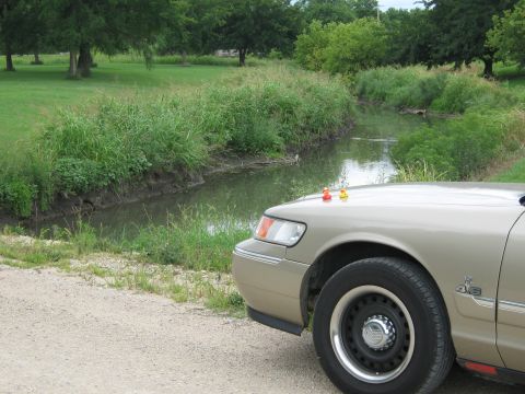 2000 Mercury Grand Marquis - Front corner of a 2000 Mercury Grand Marquis parked beside a grassy creek.