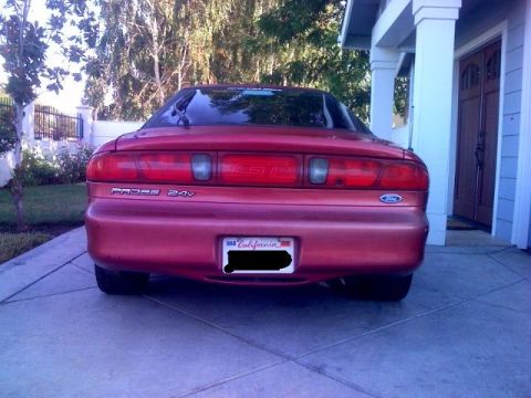 1995 Ford Probe - The rear of a red Ford Probe with 'PROBE 24V' badging is shown parked in front of a house.