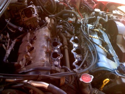 1995 Ford Probe - Close-up view of a car's engine bay with the intake manifold disassembled, revealing internal engine components and wiring harnesses.