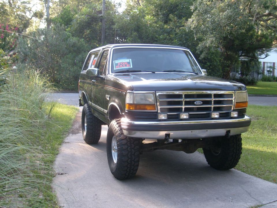 Black 1992 Ford Bronco with lifted suspension and off-road tires, parked on a driveway