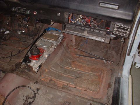 1970 Ford Torino - The interior of a car shows a transmission and exposed wiring, with significant rust on the floor pans.