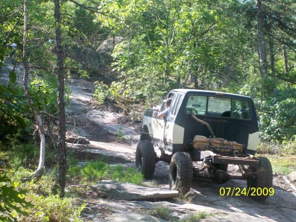 pickup truck driving on a rocky trail in the woods