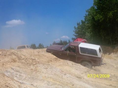 1980 Ford Bronco - A maroon 1980 Ford Bronco navigates a steep dirt incline with a white hardtop and another vehicle visible in the background.