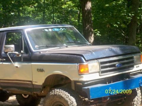 1980 Ford Bronco - Ford Bronco with aftermarket blue bumper and checkered flag sticker on windshield.