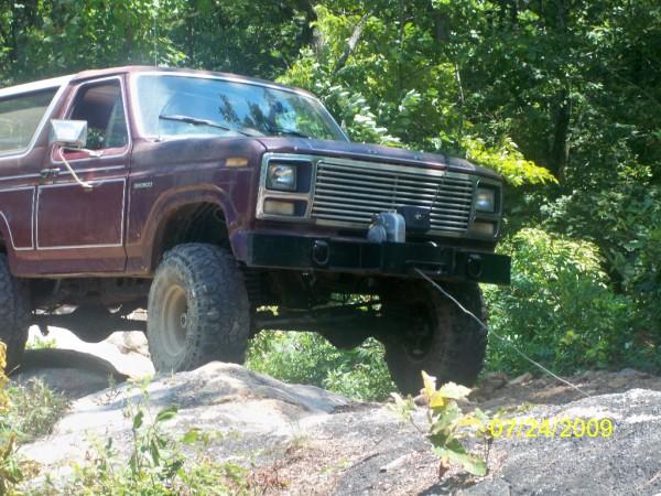 1980 Ford Bronco on rocky terrain with trees in background