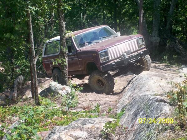Maroon 1980 Ford Bronco off-roading on rocks and dirt