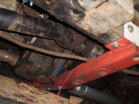 1978 Ford Bronco - Close-up of vehicle drivetrain components, including a driveshaft and transfer case, viewed from below.