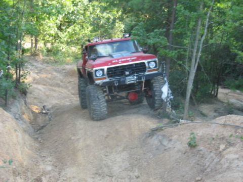 1979 Ford Bronco - Modified 1979 Ford Bronco navigating an off-road trail with large tires and a winch.
