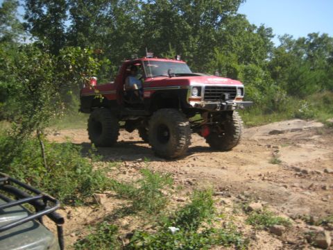 1979 Ford Bronco - A red 1979 Ford Bronco navigates a rocky off-road trail with a second vehicle partially visible in the foreground.