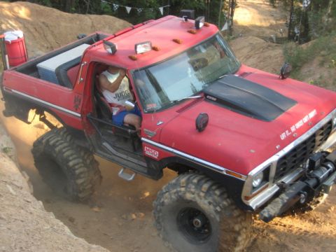 1979 Ford Bronco - Modified 1979 Ford Bronco tackling an off-road trail with large tires and a winch.
