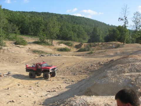 1979 Ford Bronco - A red off-road truck navigates a dusty track at an off-road park.