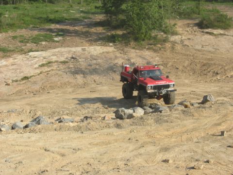 1979 Ford Bronco - Modified red pickup truck navigates a rocky off-road course.