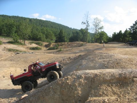 1979 Ford Bronco - A modified pickup truck navigates a challenging off-road course on a sunny day.